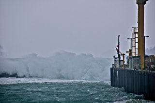 Waves crash over the jetty during a storm.